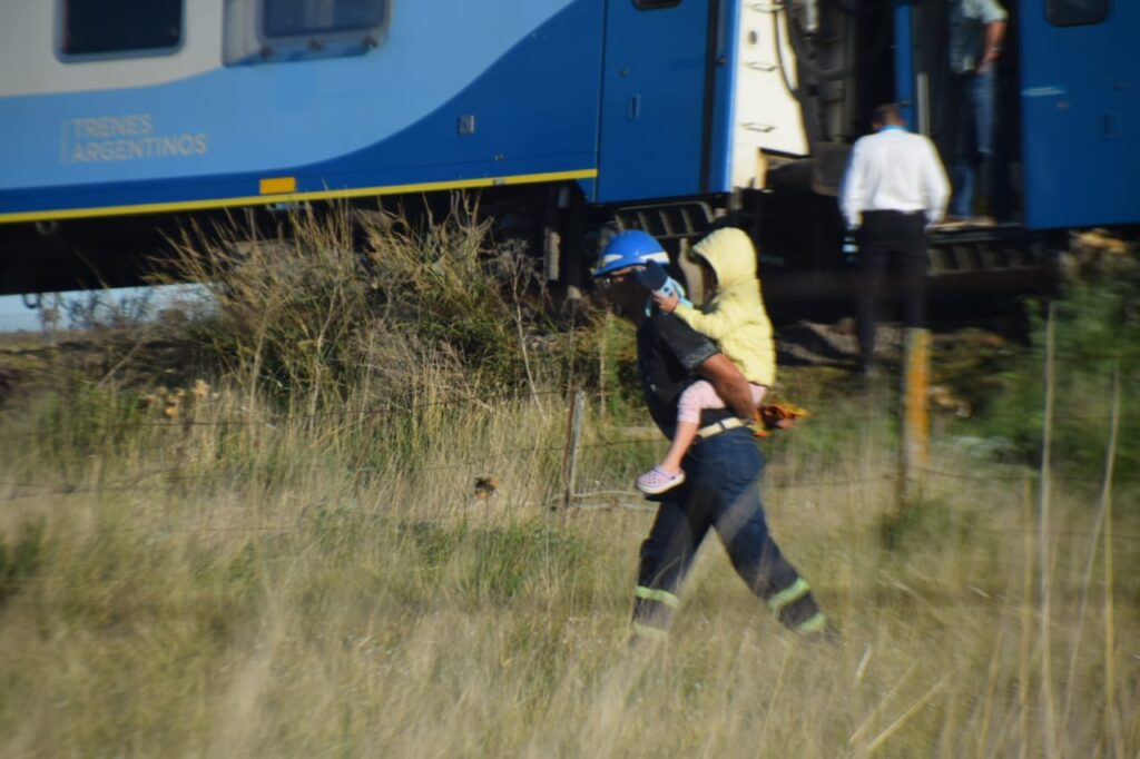 Los bomberos evacuando a los pasajeros del tren que descarriló en Olavarría. 