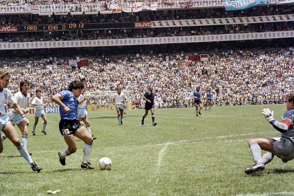 Diego Maradona durante su icónico gol a los ingleses en los Cuartos de Final de México 1986. El histórico 10 nació en Villa Fiorito, del partido de Lanús.